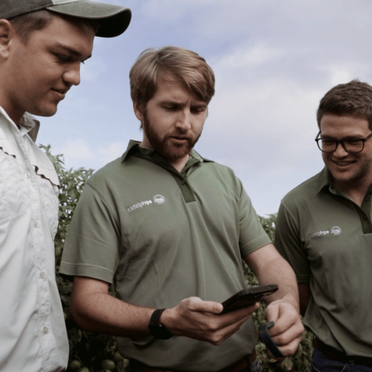 AllWage staff demonstrating a mobile device to a worker in an outdoor field setting