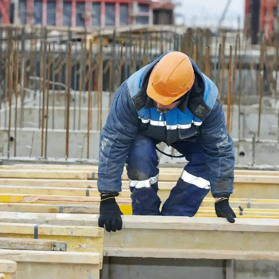 Construction worker in hard hat working on building site formwork