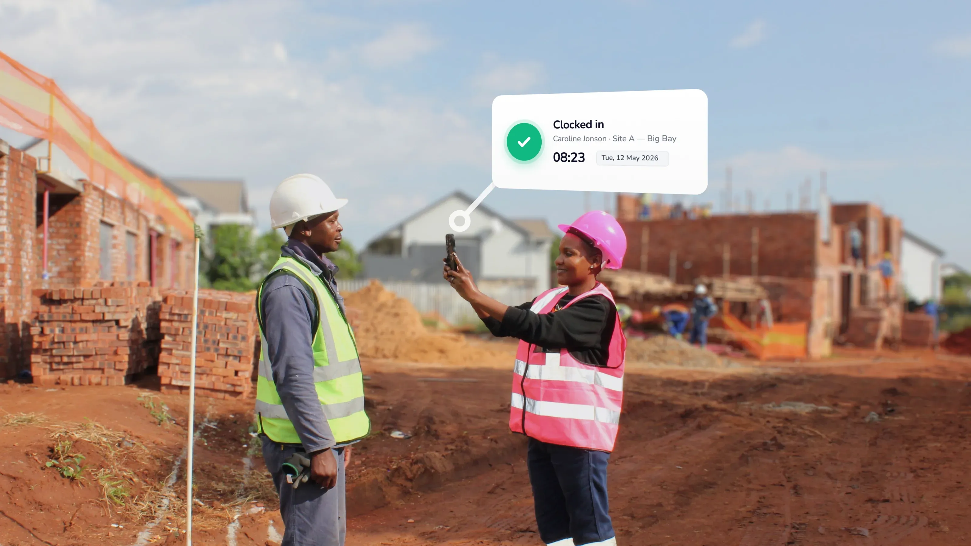 Construction worker using a mobile facial recognition clocking app to clock in another worker on site, with confirmation overlay.