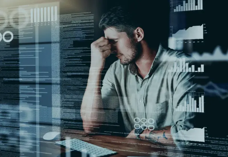 Frustrated man at a desk with digital analytics overlays, representing geotracking or workforce monitoring challenges