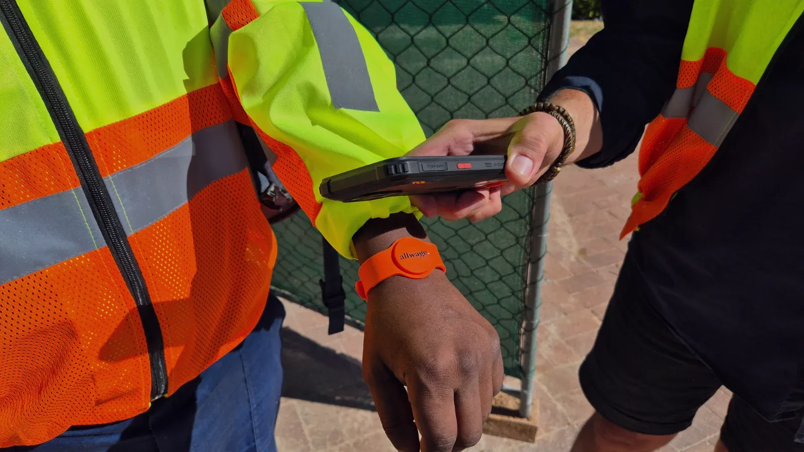 Worker wearing an RFID wristband being scanned with a rugged handheld device for time and attendance clocking